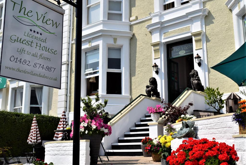 a sign in front of a guest house with flowers at The View Guest House (Adults Only) in Llandudno