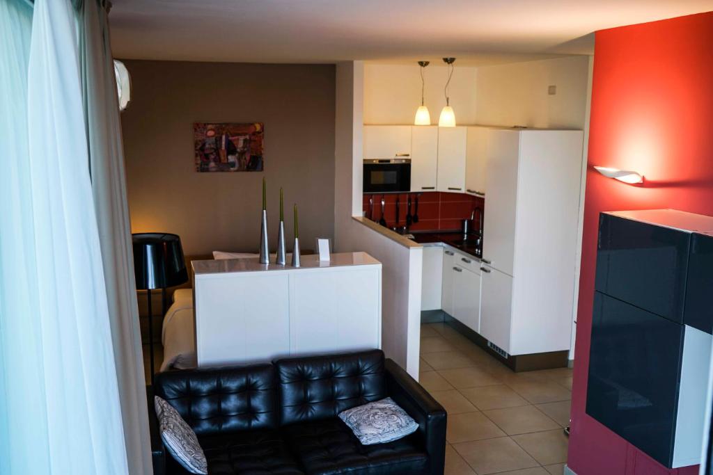a living room with a black leather chair and a kitchen at Sicilia's Art Hotel & Spa in Acitrezza