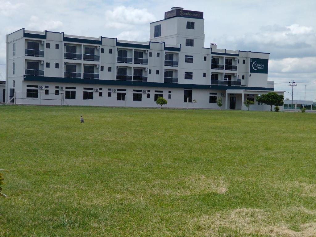 een groot wit gebouw met een veld ervoor bij Rambo Hotel in Alegrete