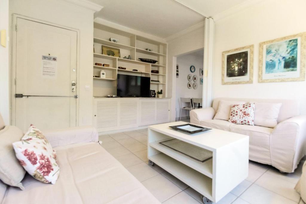 Sala de estar blanca con sofá y mesa en Rio Spot Homes Leblon U042, en Río de Janeiro