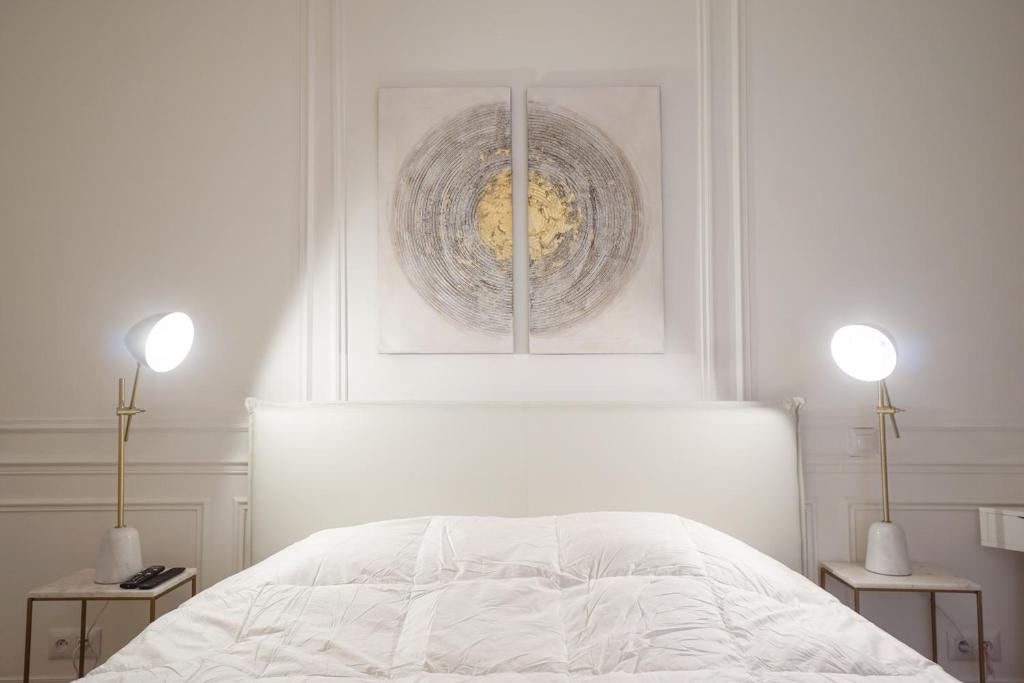 a white bedroom with a white bed and two lamps at Modern Duplex Close To The Eiffel Tower in Paris