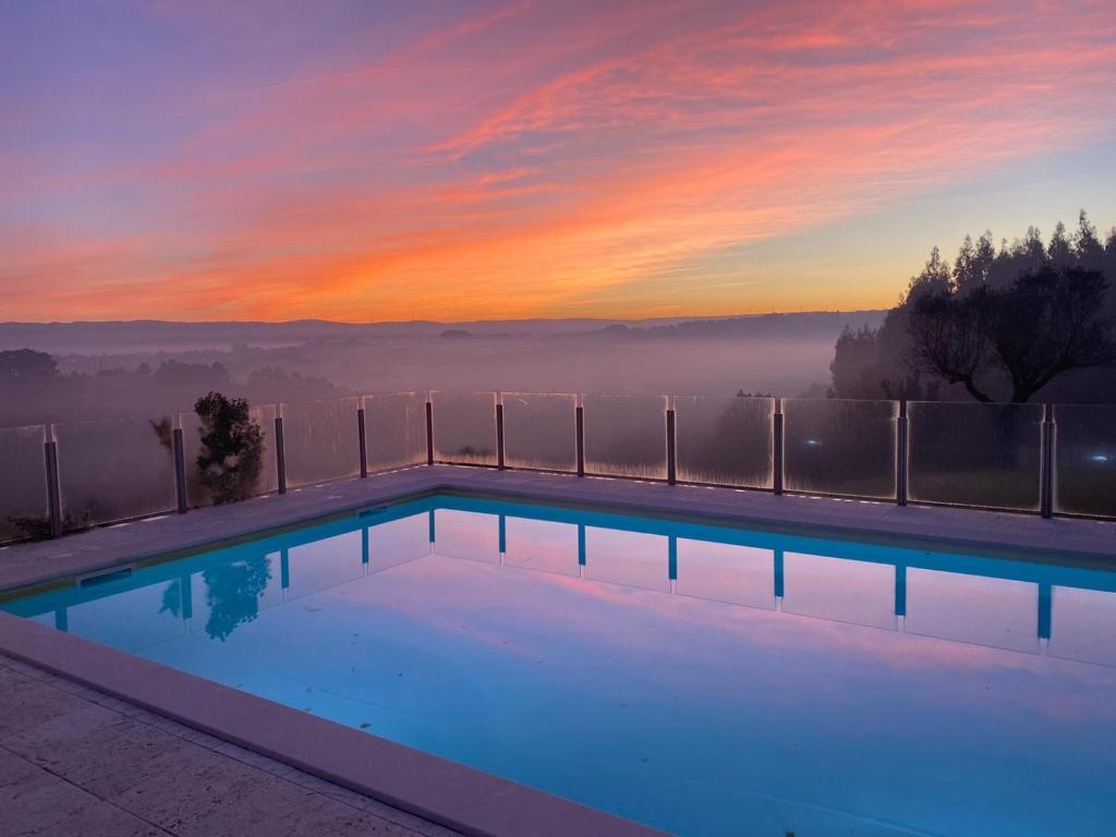 a swimming pool with a sunset in the background at Cecile's Villa in Casal do Pardo