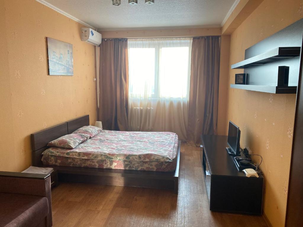 1 dormitorio con cama, escritorio y ventana en Apartments on Otradnaya and Kho Shi Mina, en Ulyanovsk