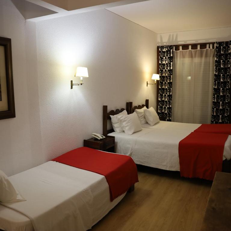 a hotel room with two beds and a window at Hotel Portofoz in Porto