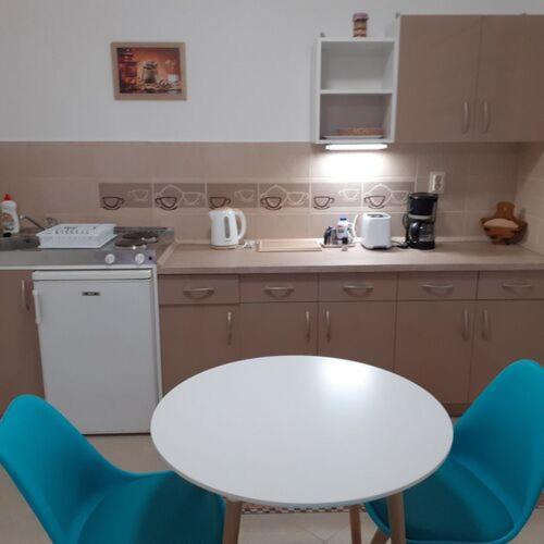 kuchnia z białym stołem i niebieskimi krzesłami w obiekcie Apartments Annamaria w Hévízie