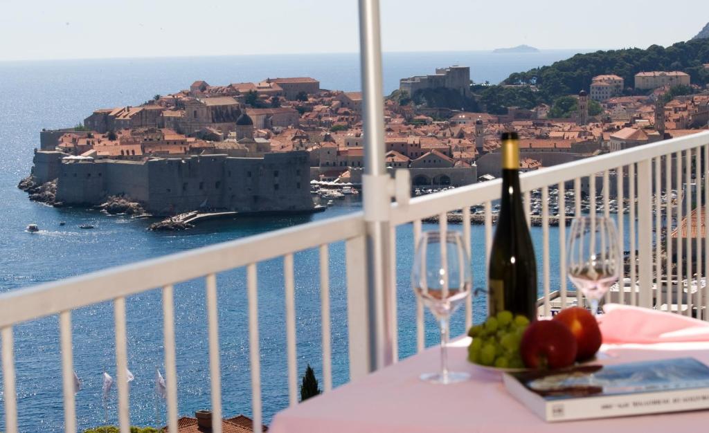 a table with a bottle of wine and glasses on a balcony at Sipa Apartments in Dubrovnik