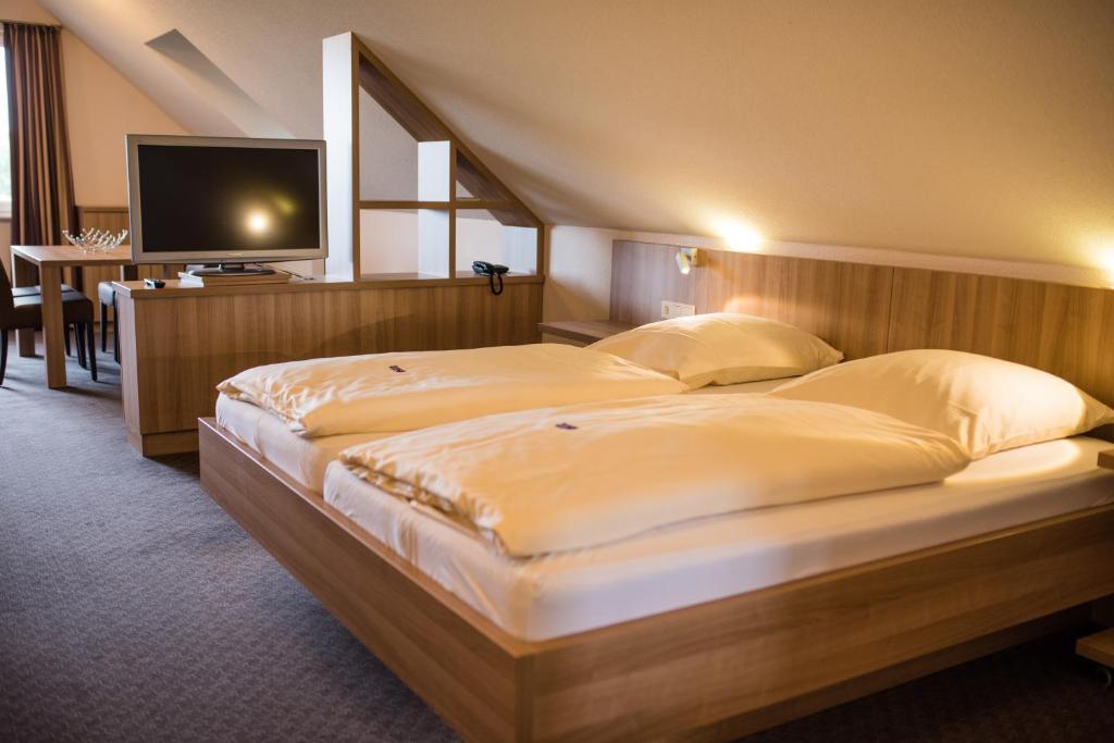 a bedroom with a large bed with a television on it at Hotel Heilemann in Wietmarschen