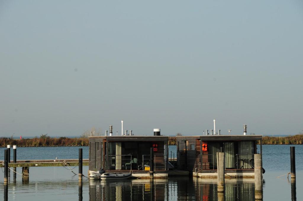 a small house on the water next to a dock at Mermaid- Hausboote in Lelystad