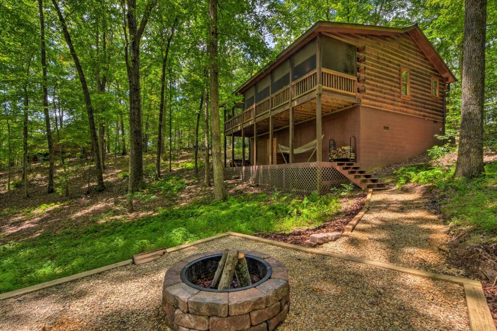 una cabaña de madera en el bosque con una hoguera en Pinot and Pine Chic Log Cabin about 5 Mi to Blue Ridge en Blue Ridge