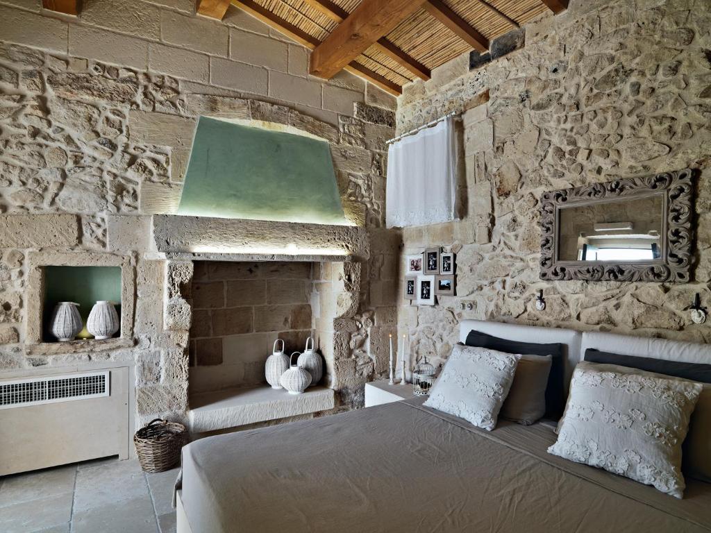 a bedroom with a bed and a stone wall at Relais Masseria Capasa in Martano