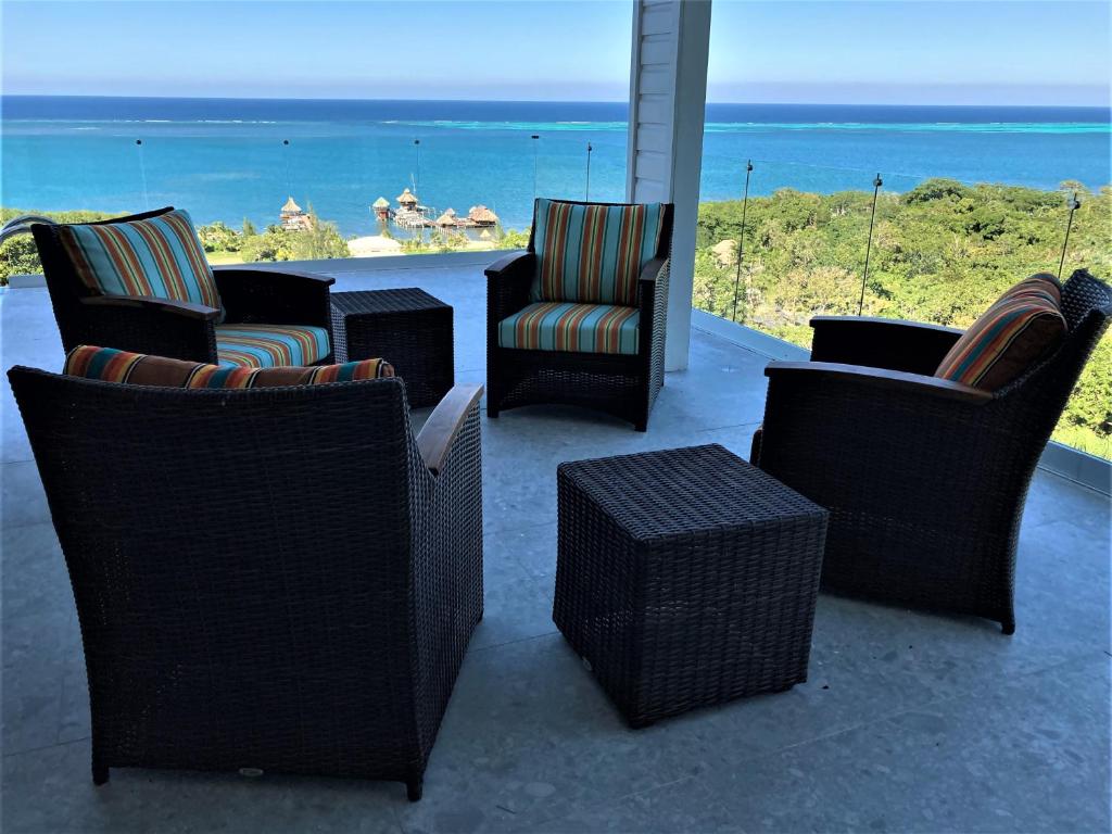 a group of chairs and tables on a patio with the ocean at Turquoise Views at Coral Views Village in French Harbour