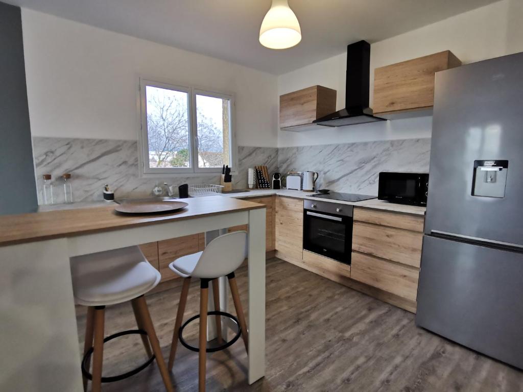 een keuken met een koelkast en een aanrecht met krukken bij Beau T4 lumineux au calme, grande terrasse in Roques Sur Garonne