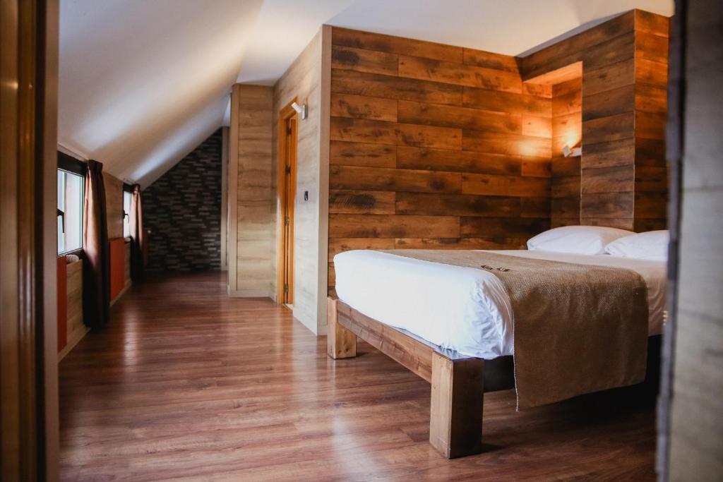 - une chambre avec un lit et un mur en bois dans l'établissement Cal Ruiz, au Pas de la Case