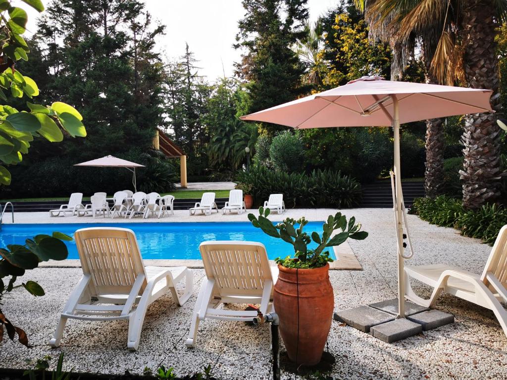a patio with chairs and an umbrella and a pool at Villa Solaria in Santa Venerina