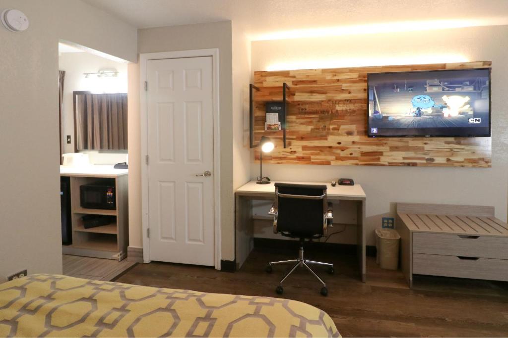 a bedroom with a desk and a tv on a wall at Baymont by Wyndham Gatlinburg On The River in Gatlinburg