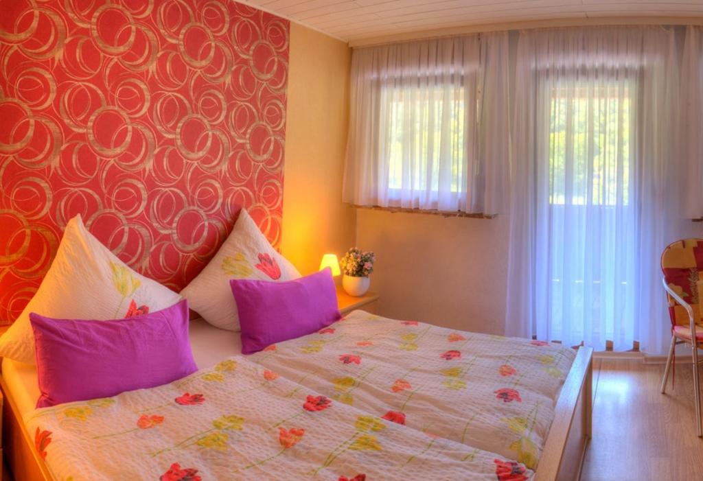 - une chambre avec un grand lit et des oreillers violets dans l'établissement Weingut und Pension Markus Kochems, à Mesenich