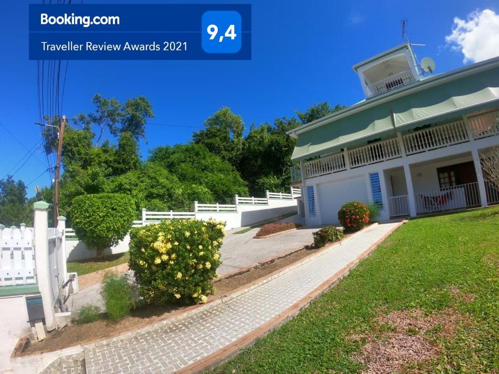 ein weißes Haus mit einem weißen Zaun und einem Hof in der Unterkunft Résidence la perle in Deshaies