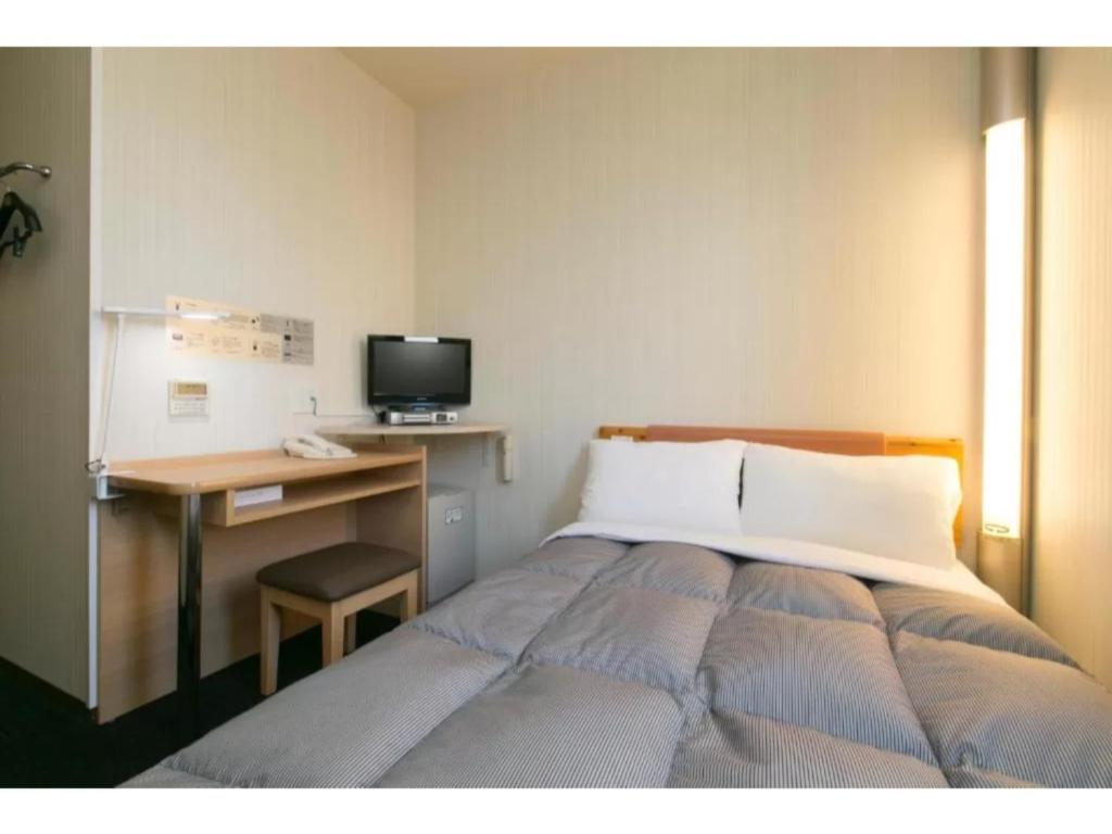 um quarto com uma cama e uma secretária com um computador em R&B Hotel Nagoya Nishiki - Vacation STAY 15171v em Nagoia
