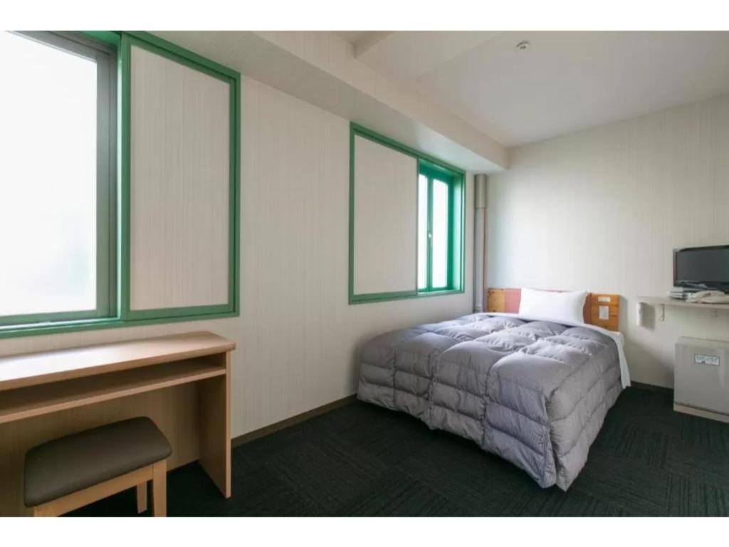 een slaapkamer met een bed, een bureau en 2 ramen bij R&B Hotel Nagoya Nishiki - Vacation STAY 15165v in Nagoya