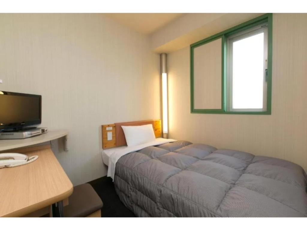 a bedroom with a bed and a desk and a window at R&B Hotel Nagoya Nishiki - Vacation STAY 15159v in Nagoya
