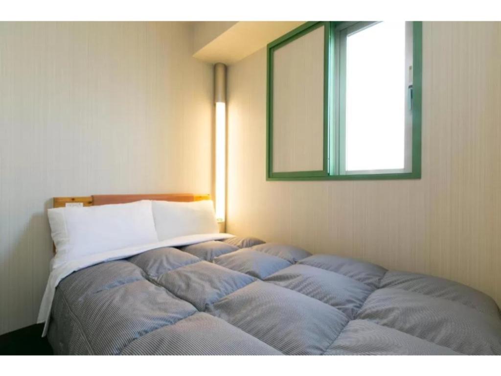 a bed in the corner of a room with a mirror at R&B Hotel Nagoya Nishiki - Vacation STAY 15170v in Nagoya