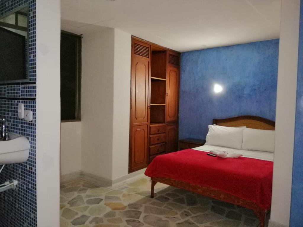 a bedroom with a red bed and a blue wall at HOTEL YORYTANIA BOUTIQUE in Pitalito