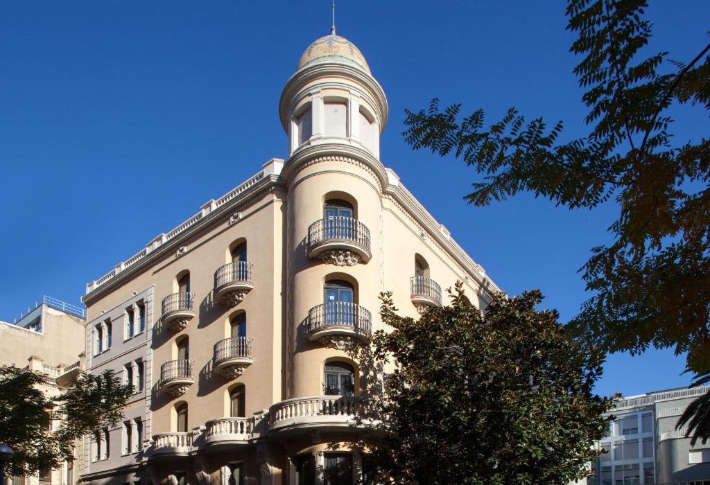 ein hohes Gebäude mit einem Turm darüber in der Unterkunft Residència Erasmus Gracia in Barcelona