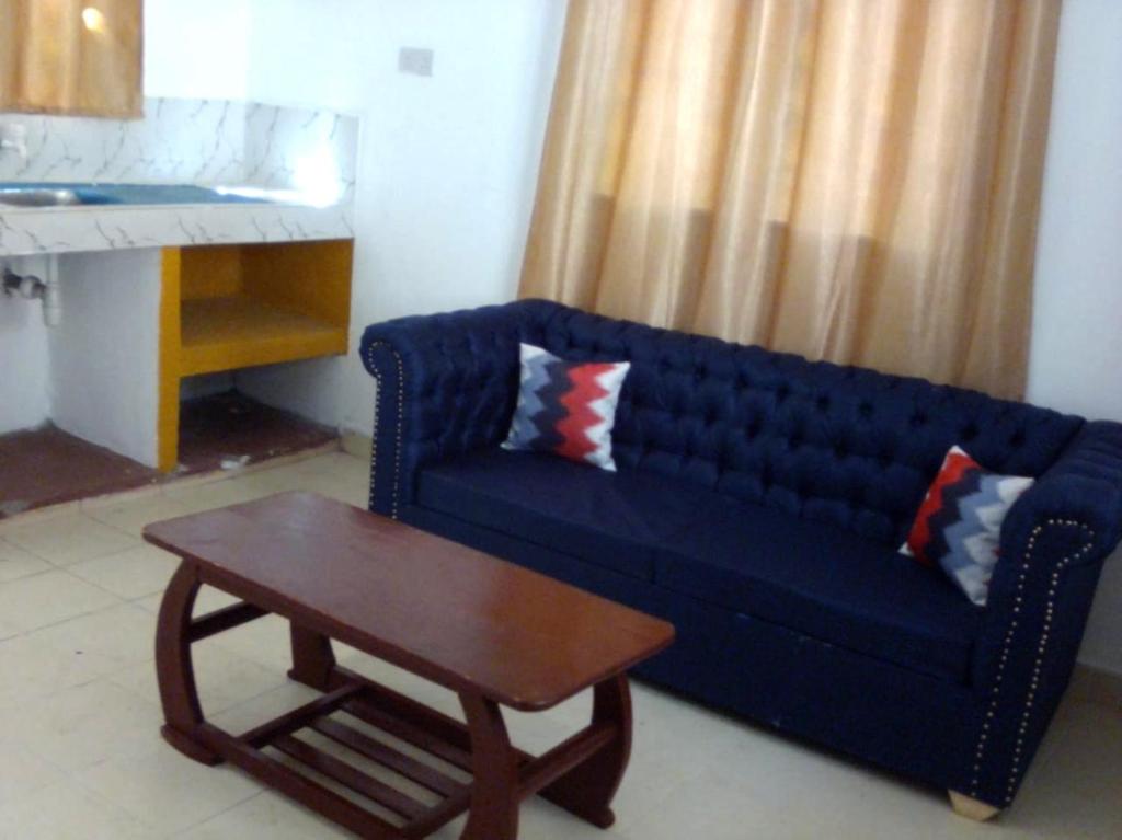 ein Wohnzimmer mit einem blauen Sofa und einem Couchtisch in der Unterkunft Brink Breeze Guest Rooms & Apartments in Mombasa