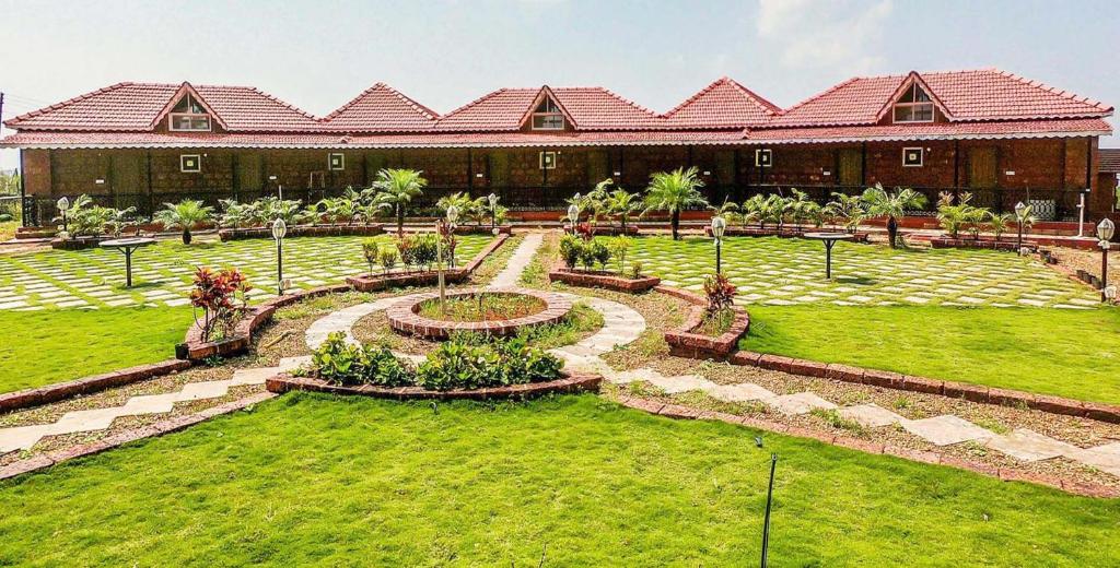 a building with a garden in front of a building at Kabila Agro Tourism in Mahabaleshwar