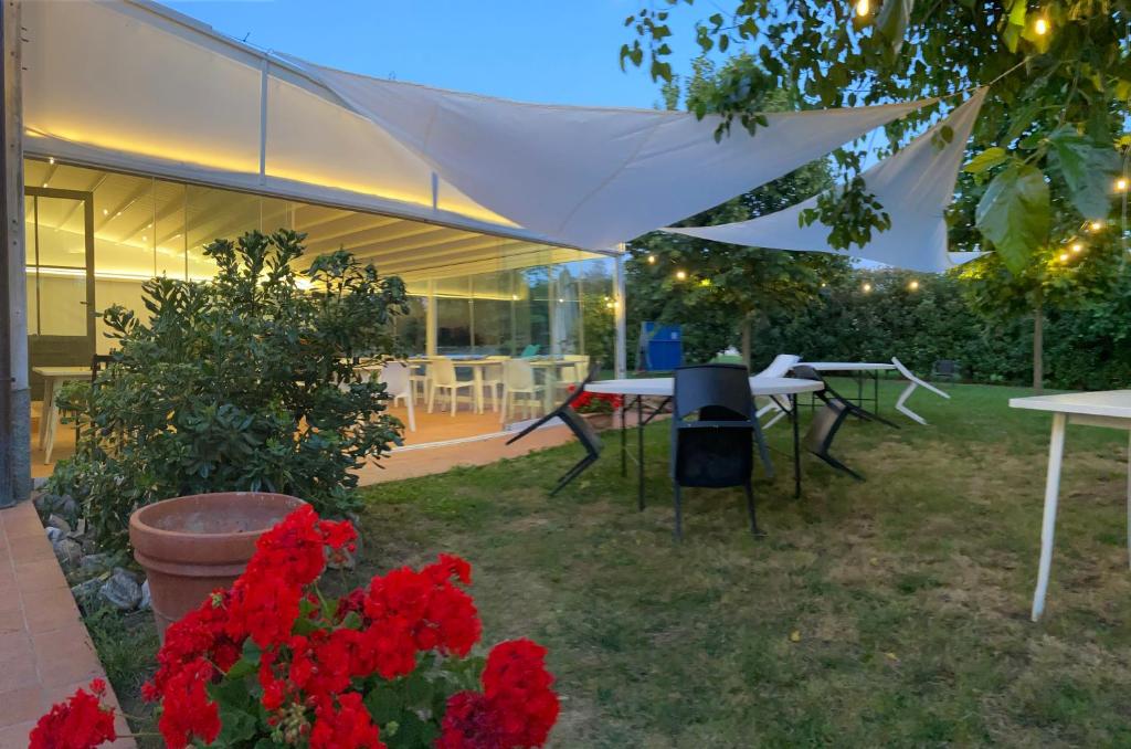 un patio con mesas y flores rojas en el patio en La Scuderia en Sarzana