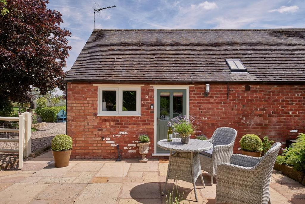 a small red brick house with a table and chairs at The Couple's Retreat in Ashbourne