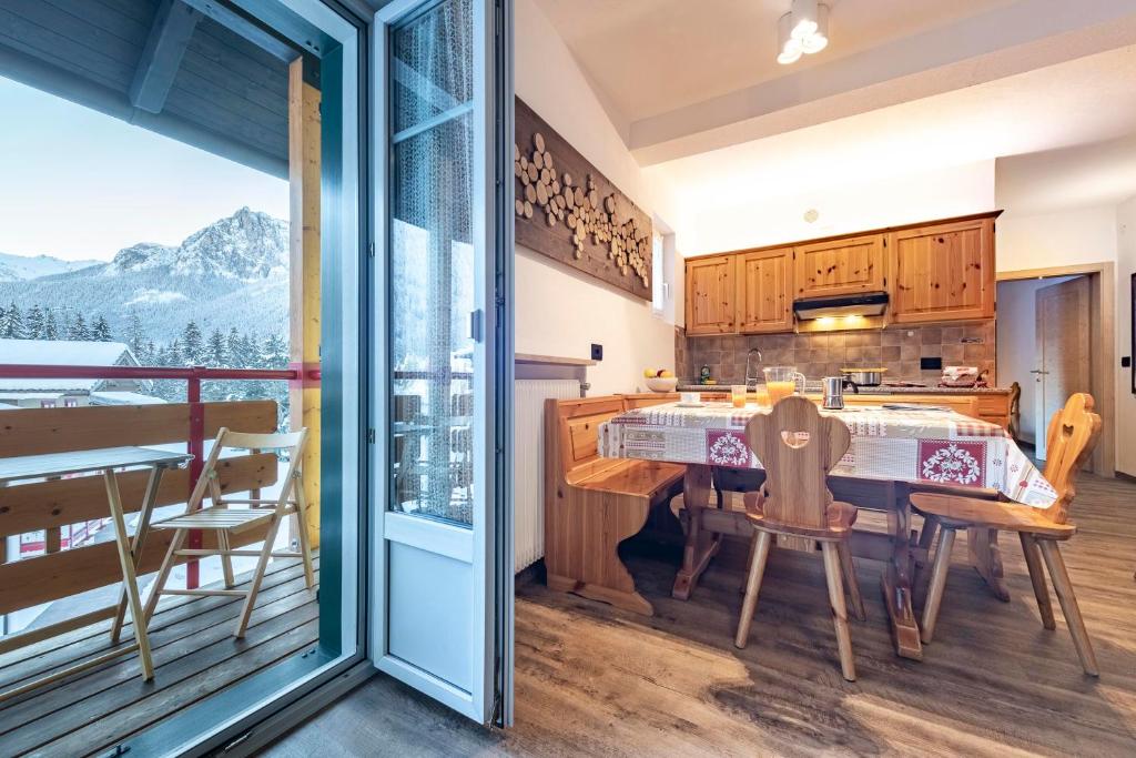 una cucina con tavolo e sedie e un balcone di Appartamenti Residence La Roggia a Pozza di Fassa