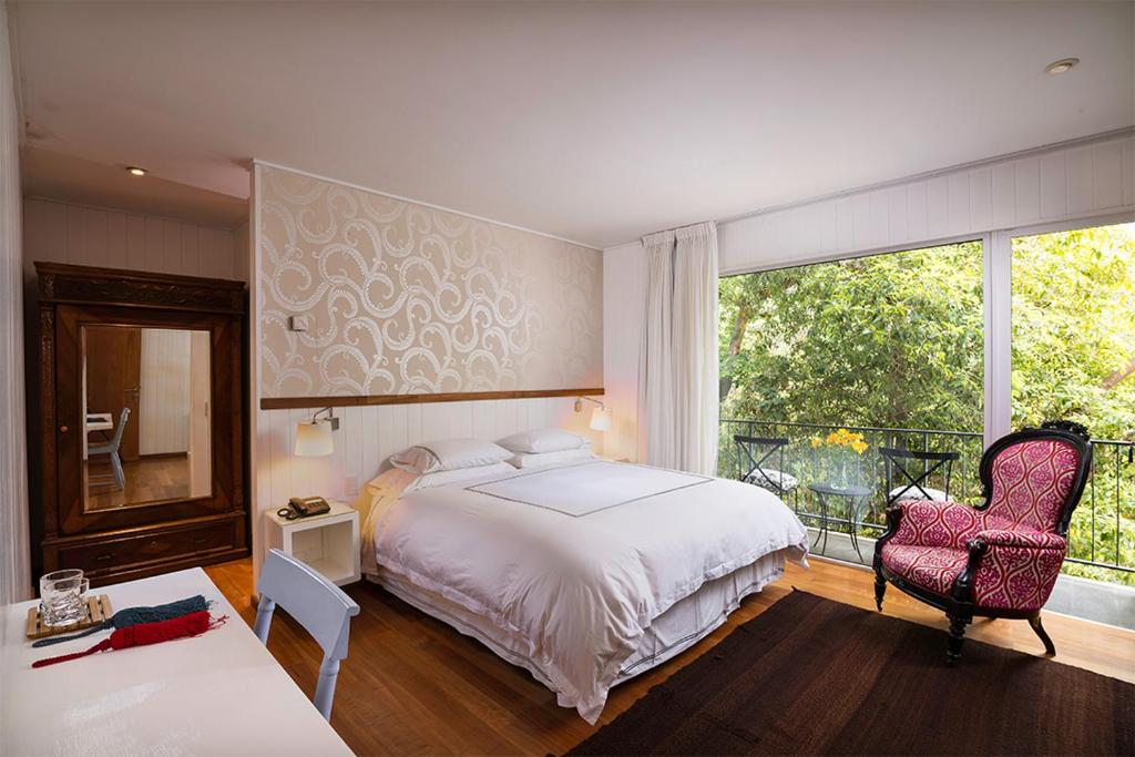 1 dormitorio con 1 cama, 1 silla y 1 ventana en Hotel Casa Zapallar en Zapallar