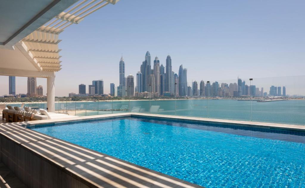a large swimming pool in front of a large building at Eden's Dubai - FIVE Palm Residences in Dubai