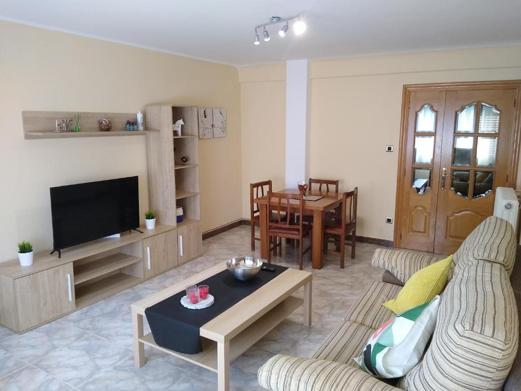 - un salon avec un canapé, une télévision et une table dans l'établissement Apartamentos La Rosa - Calamocha, à Calamocha