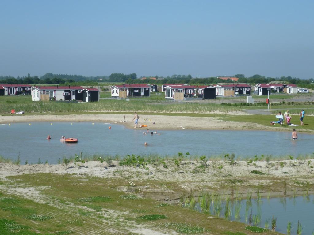 eine Gruppe von Menschen, die in einem Wasserkörper schwimmen in der Unterkunft Chaletverhuur-Olmenduin in Serooskerke