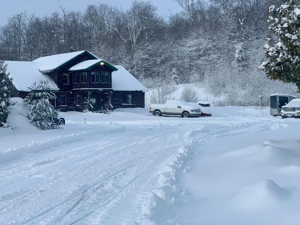 a house covered in snow with cars parked in the driveway at Tug Hill Resort in Redfield