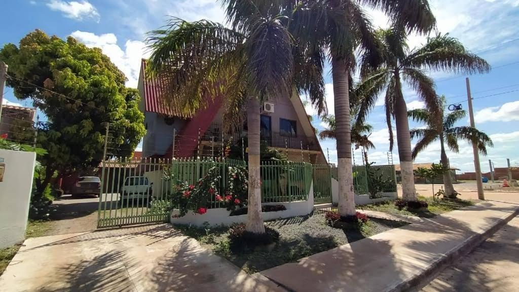 een huis met palmbomen en een hek bij Segundo andar de chalé suiço in Luis Eduardo Magalhaes