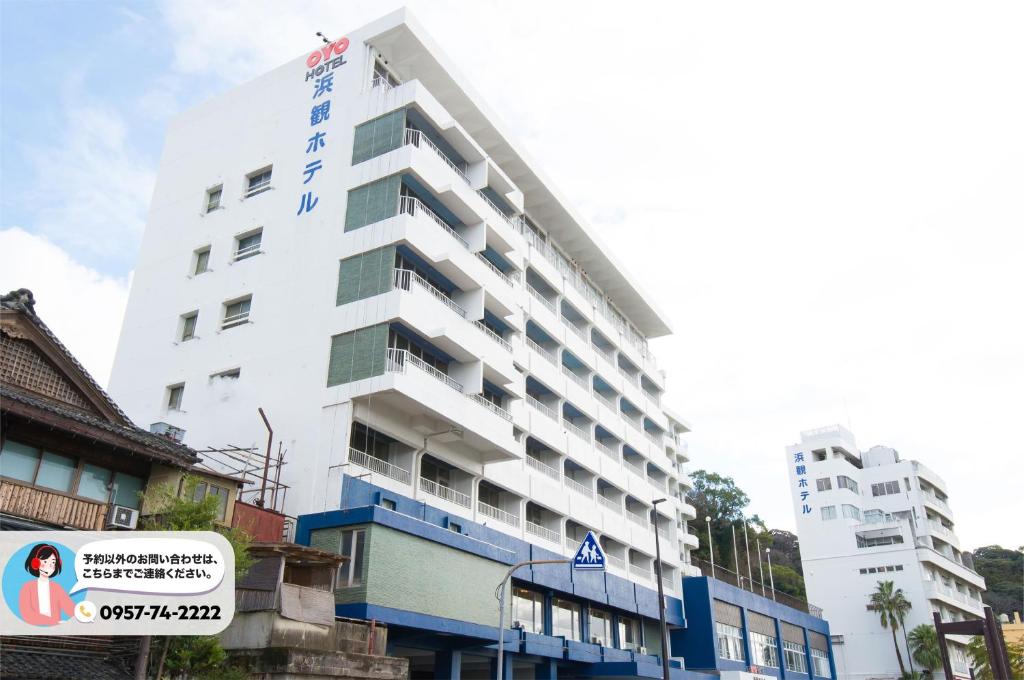 um edifício branco com um sinal em frente em Obama Onsen Hamakan Hotel em Unzen