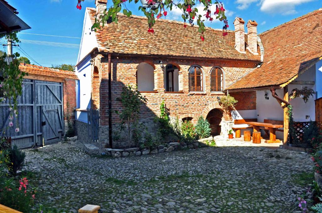 uma velha casa de tijolos com um banco em frente em Casa Nicu em Vale