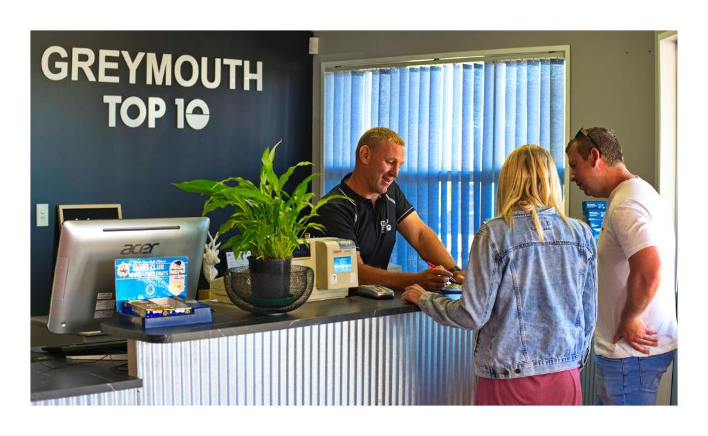 eine Gruppe von Menschen, die in einem Büro um einen Tresen stehen in der Unterkunft Greymouth Seaside TOP 10 Holiday Park in Greymouth