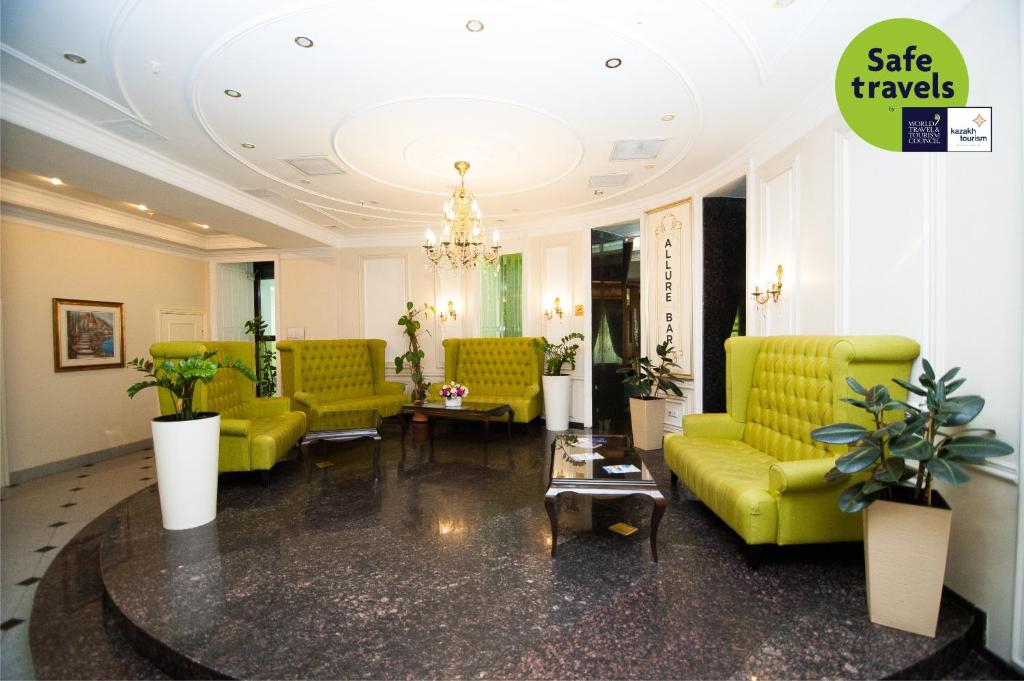 a lobby with yellow furniture and a chandelier at Kazzhol Hotel Astana in Astana