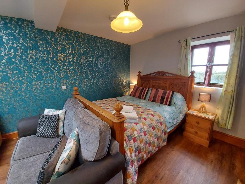 a bedroom with a bed and a couch at Dog friendly detached studio - Up to 3 Guests can stay - Only 3 Miles from Lyme Regis - Large shower ensuite -Kitchen - Small fenced garden - Free private parking in Axminster