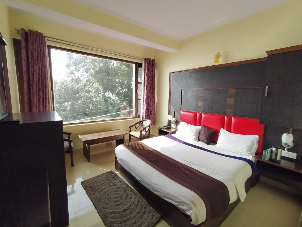 a bedroom with a large bed with a large window at Hotel The Super Mall Residency, Mussoorie in Mussoorie