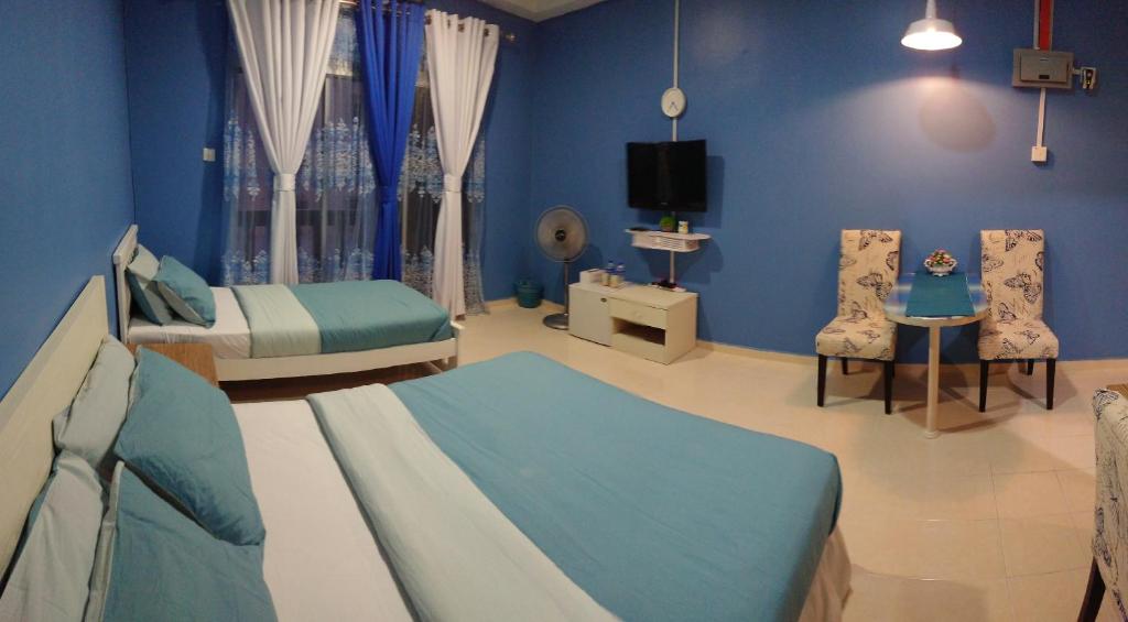 um quarto azul com duas camas e uma televisão em AlRayani Guest Room, Homestay Kota bharu em Kota Bharu