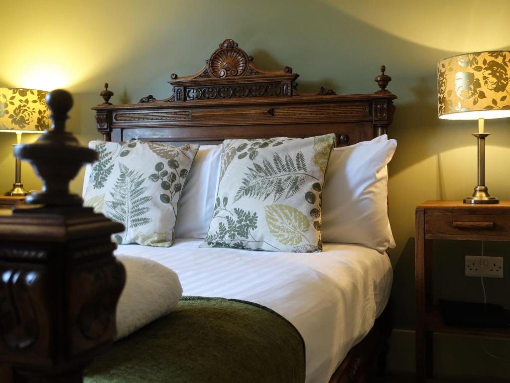 a bed with a wooden headboard and pillows at One Holyrood Hotel & Cafe in Newport