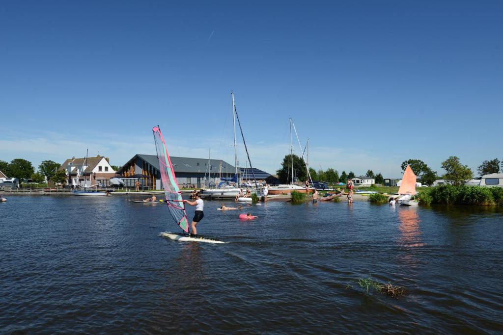 een persoon op een bord met een zeil op het water bij Gouden Plakje in Gaastmeer