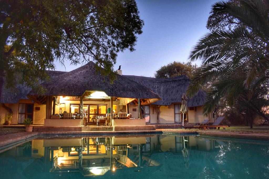 a house with a swimming pool in front of it at Mziki Safari Lodge in Vaalkop Dam