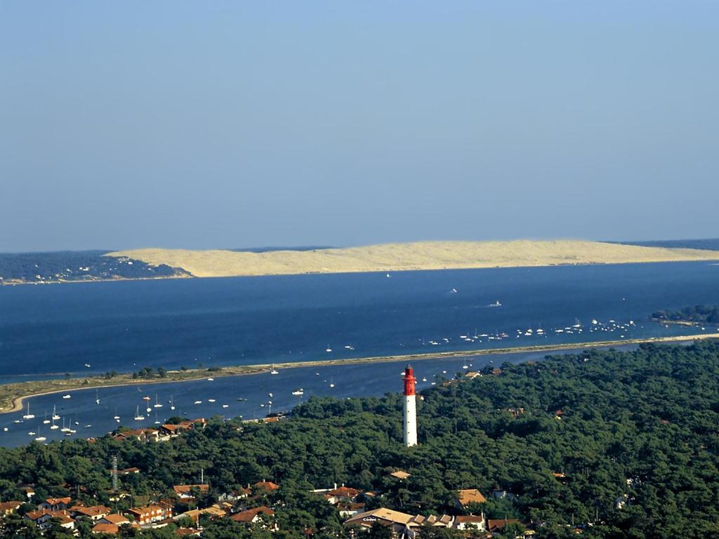 a red and white lighthouse on a island in the water at La cabane du Truquet in Lège-Cap-Ferret