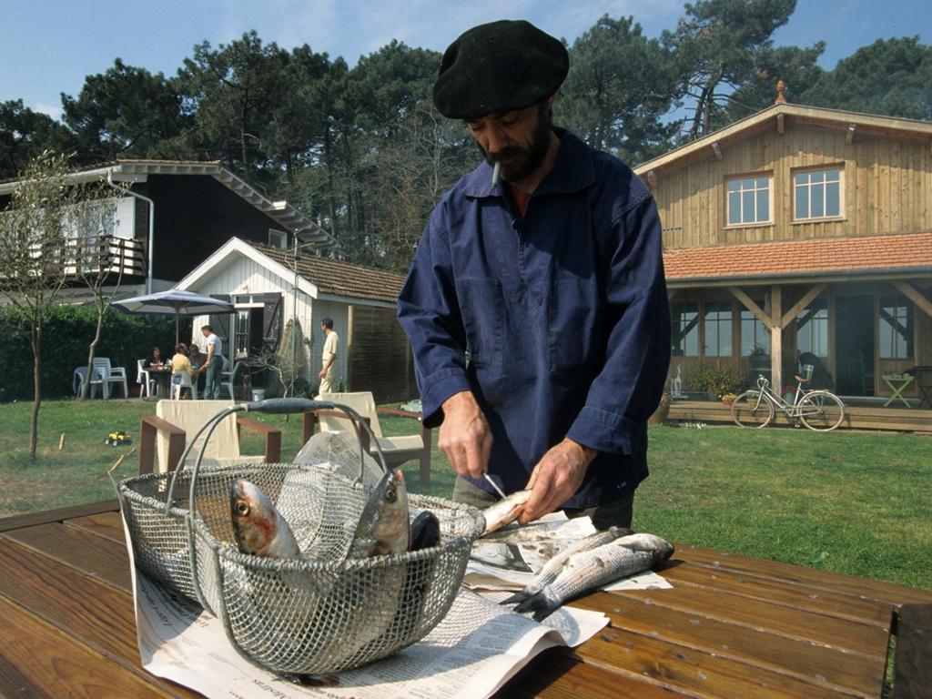 a man cutting a fish in a basket on a table at La cabane du Truquet in Lège-Cap-Ferret